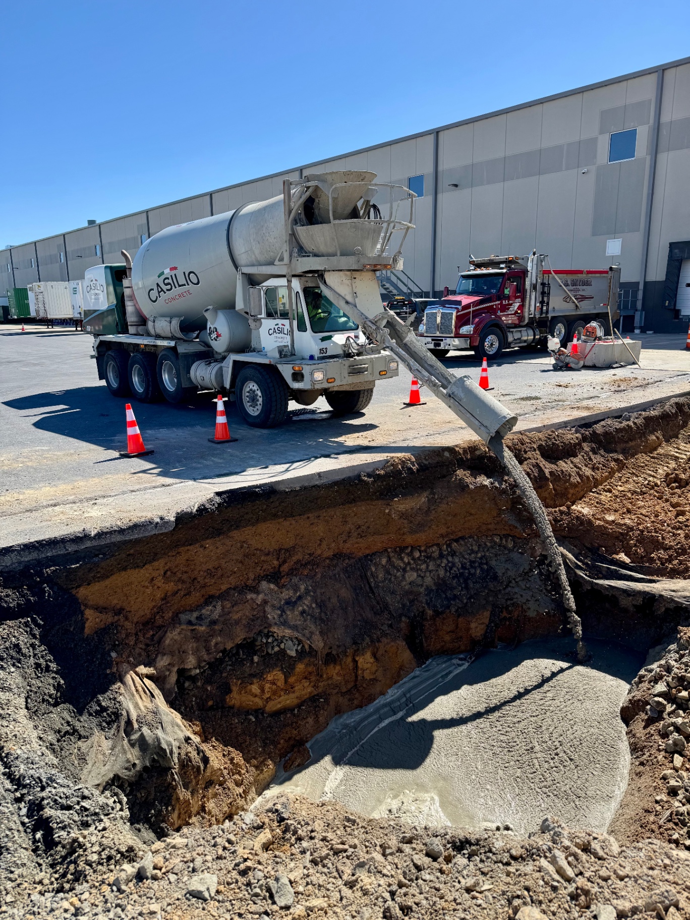 Concrete truck discharging into an active utility trench