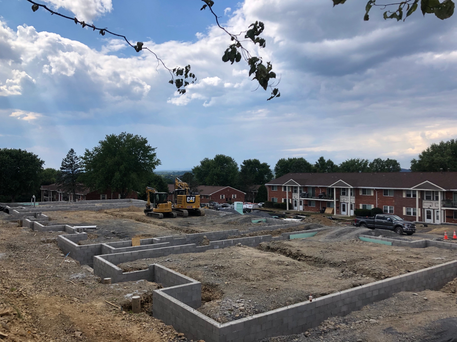 Block foundation walls laid out for a multi-unit residential build with CAT excavators on site